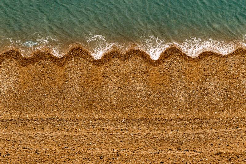 A beach with wavy shoreline seen from above