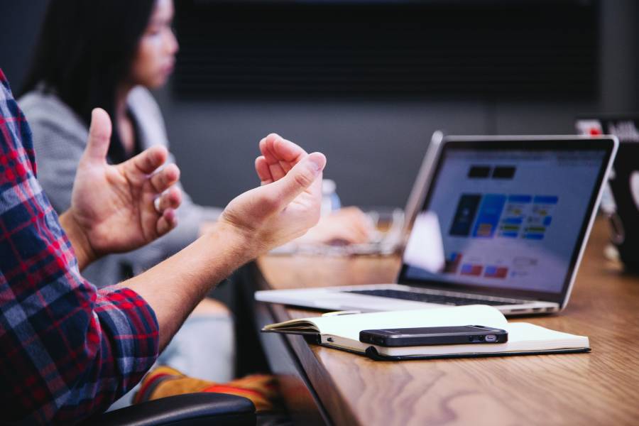 A person explaining something during a meeting with a laptop in front of them